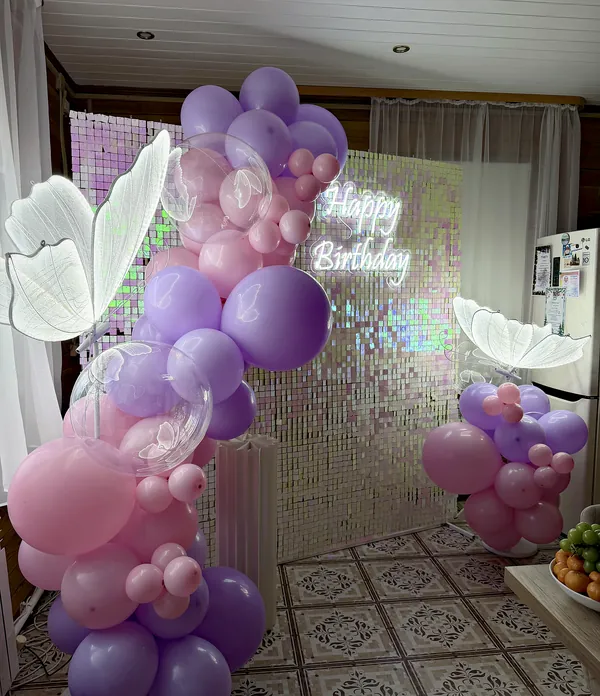 Перламутровая пайеточная стена с неоновой надписью «Happy Birthday», гирлянда из фиолетовых, сиреневых и розовых шаров и светящиеся бабочки